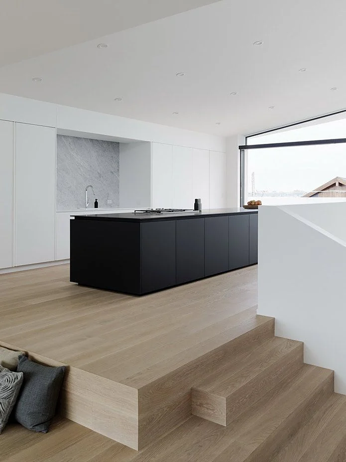 Black matt kitchen island with white floor-to-ceiling tall units and a marble niche Black matt kitchen island with white floor-to-ceiling tall units and a marble niche